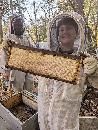 Beekeepers holding a capped frame of honey